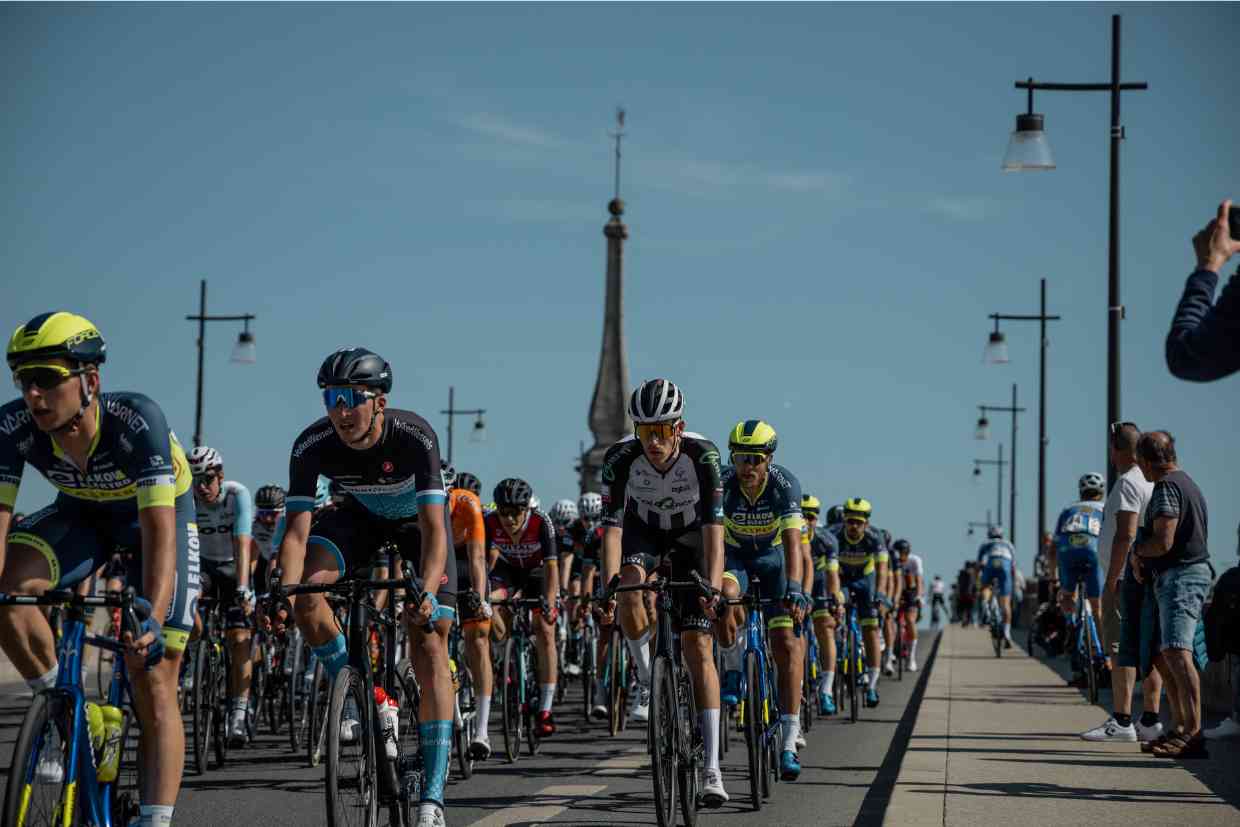 Grupo de ciclistas profissionais em competição, todos usando capacetes MIPS em um pelotão.