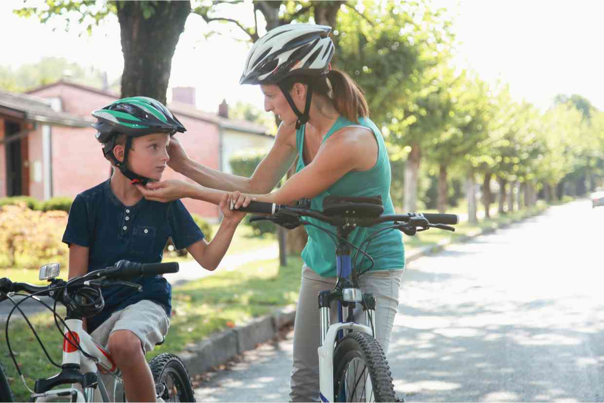 Mãe ajustando capacete MIPS em seu filho antes de um passeio de bicicleta.