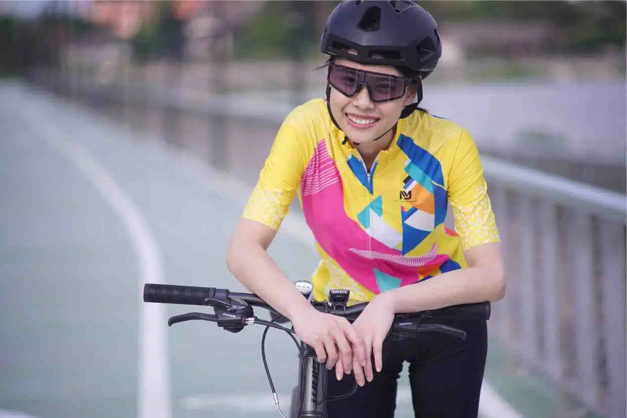 Mulher ciclista sorridente em pausa, recuperando-se da fadiga muscular após atividade física.