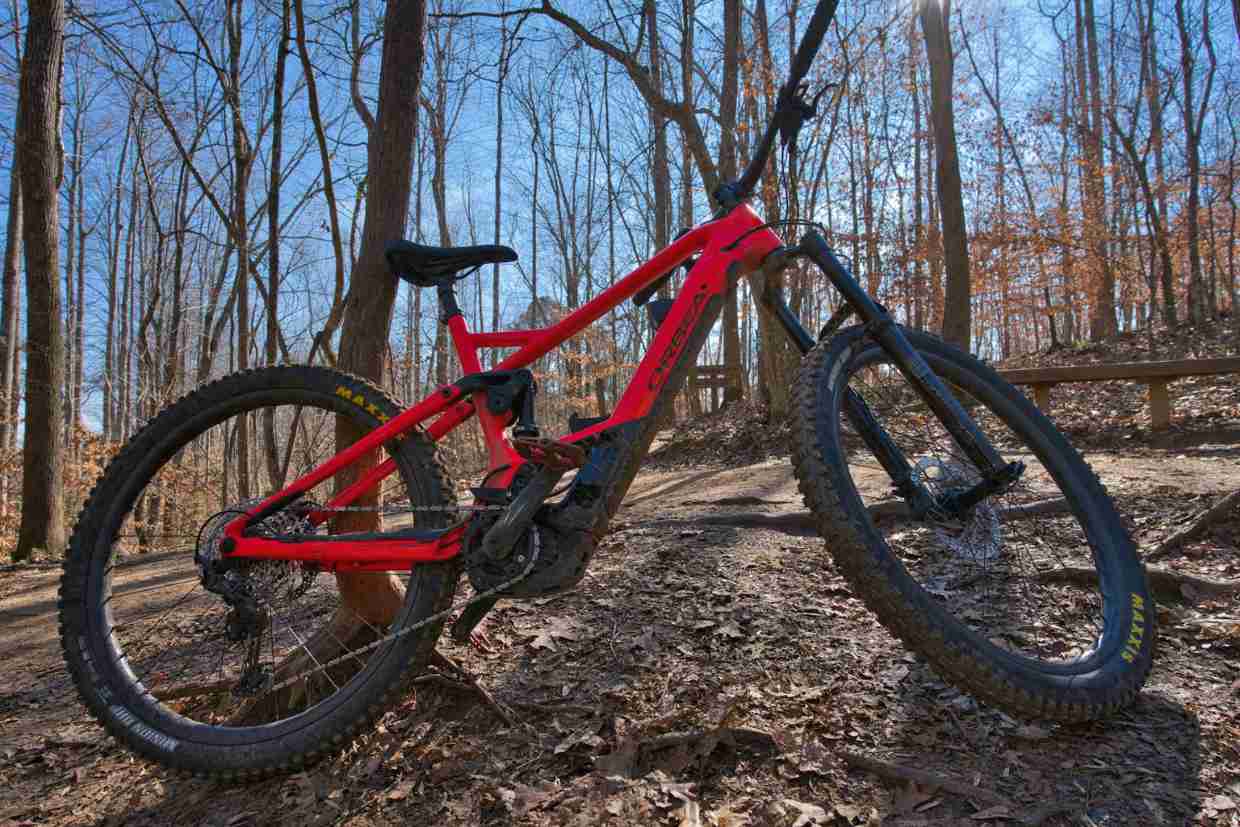Bicicleta de trilha apoiada em árvore em percurso seco de mountain bike no meio do bosque.