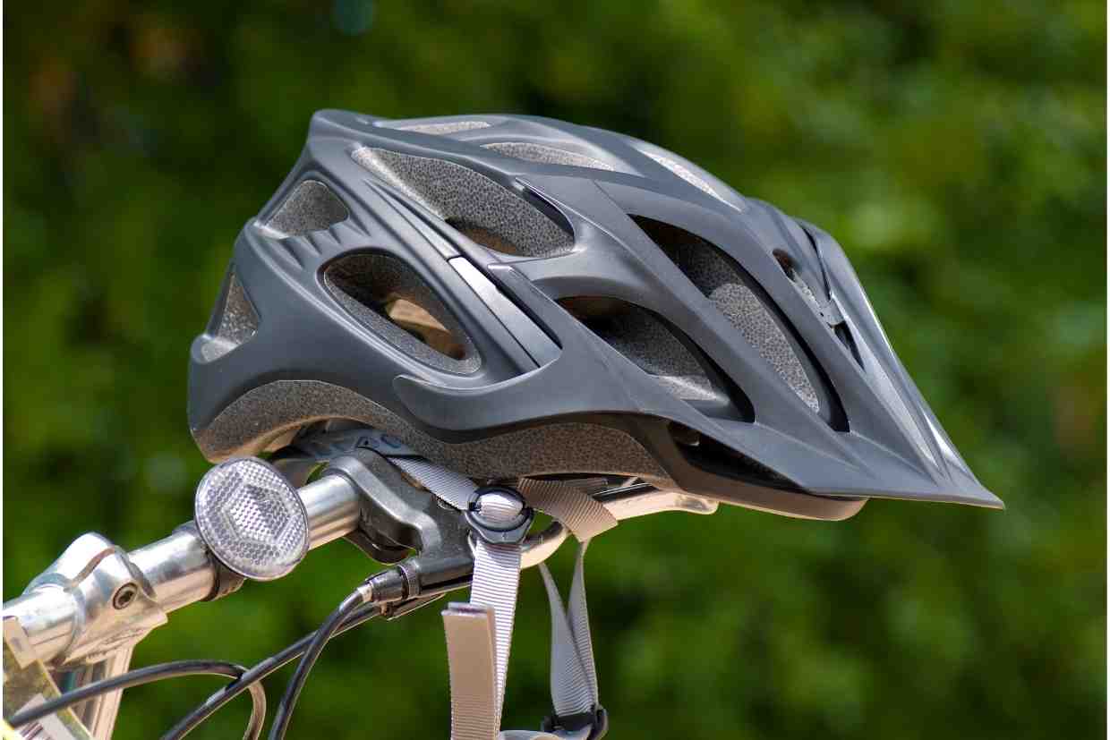 Capacete inteligente preto fixado no guidão da bicicleta com iluminação acoplada.