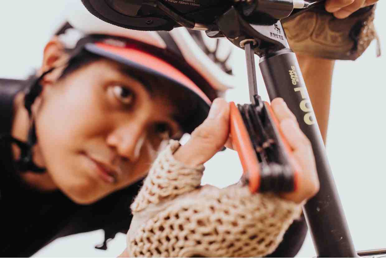 Ciclista ajustando o selim da bicicleta com uma ferramenta multitool. Um bom bike fit começa com o ajuste correto da altura e posição do selim.