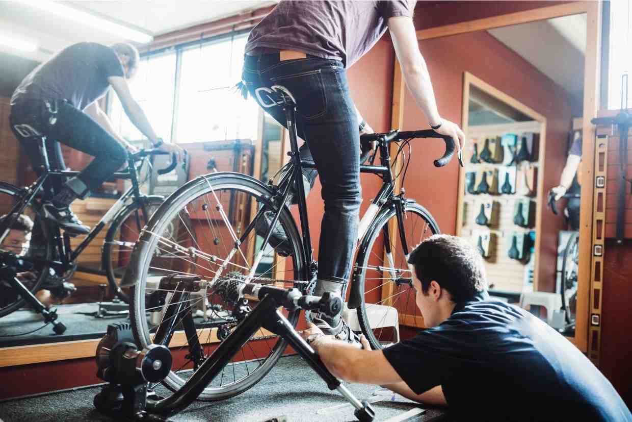 Profissional realizando bike fit em ciclista com bicicleta sobre rolo de treino
