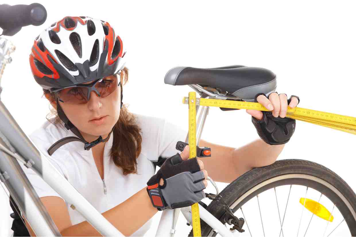 Ciclista utilizando fita métrica para medir altura do selim da bicicleta.