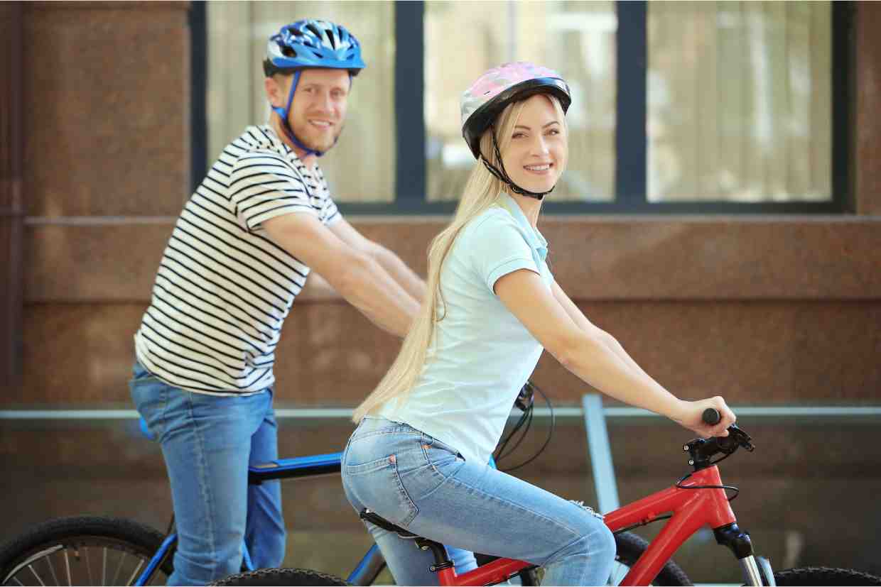 Casal de ciclistas sorridentes usando suas mountain bike para iniciantes enquanto pedalam pelas ruas da cidade.