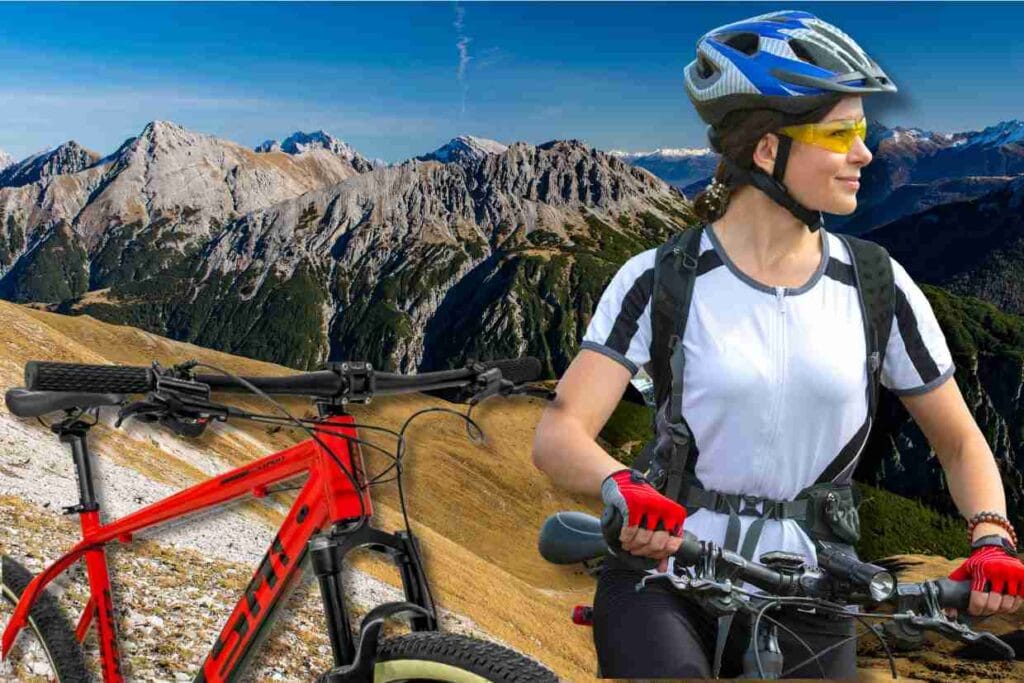 Ciclista com capacete e óculos ao lado de uma bicicleta GTS M1 vermelha, com paisagem de montanhas ao fundo.