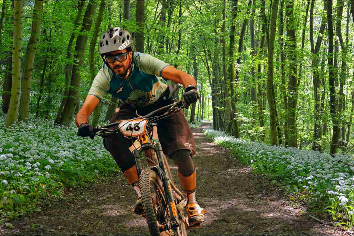 Ciclista competindo em trilha de floresta, pedalando uma bicicleta GTS M1 equipada para provas de mountain bike.