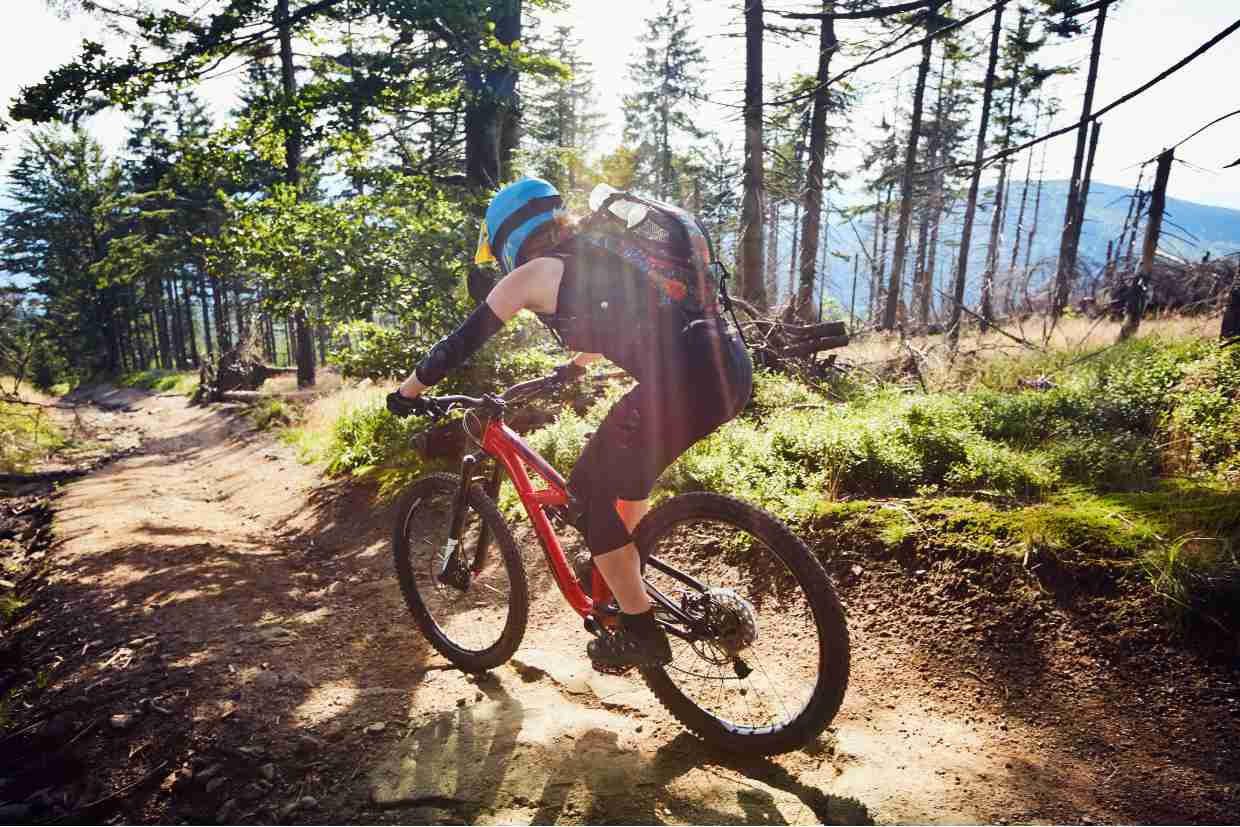 Ciclista pedalando em trilha de terra, curvando-se em descida com sua bicicleta GTS M1 vermelha.