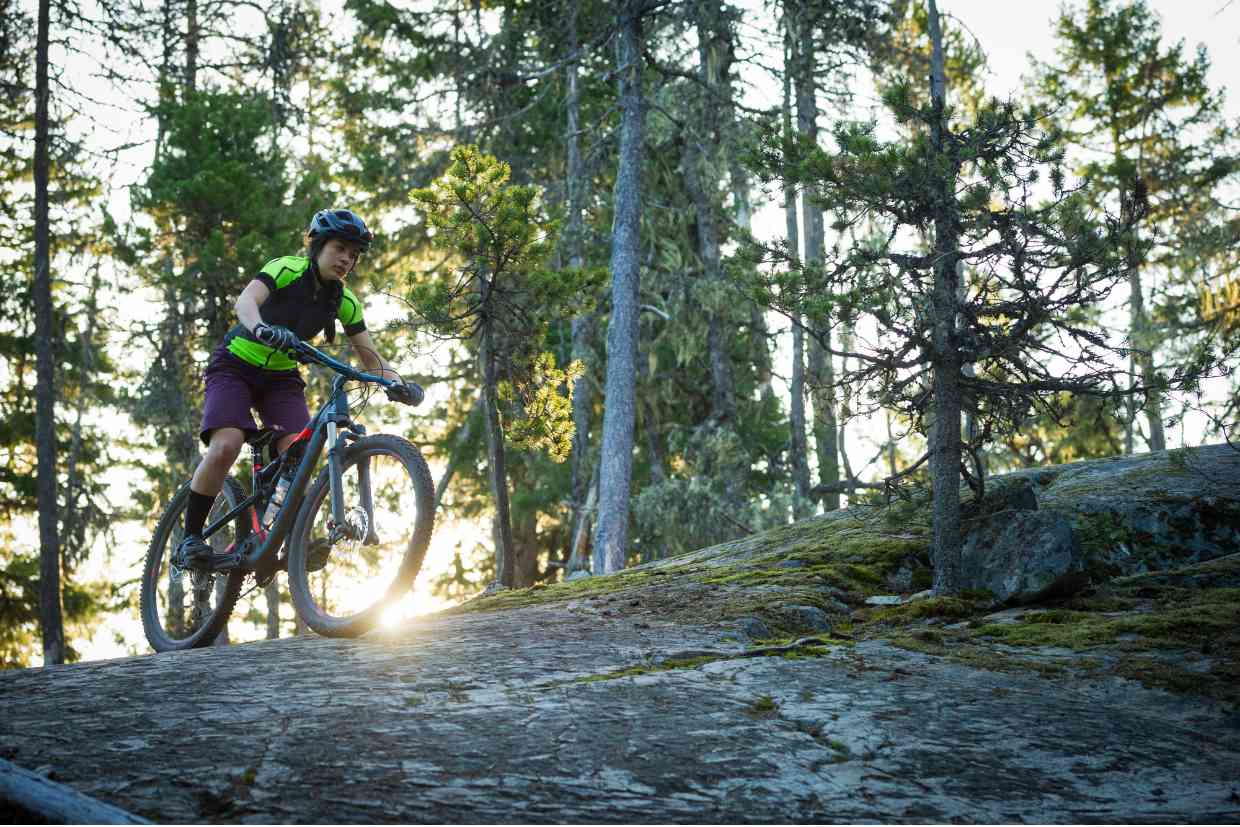 Ciclista pedalando em subida de pedra com uma bicicleta aro 29 sob a luz do pôr do sol.