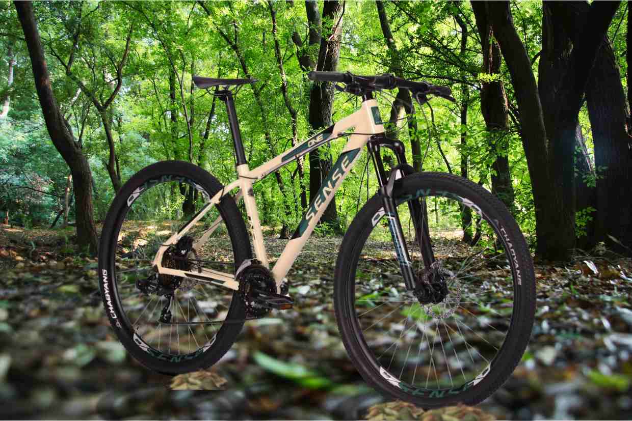 Bicicleta aro 29 Sense One em trilha de floresta com chão coberto de folhas.