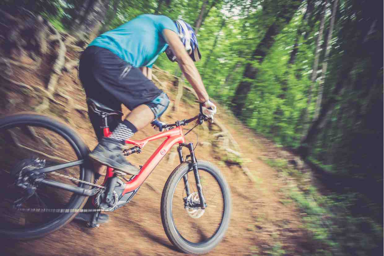 Ciclista com capacete enduro MTB em movimento rápido, florestal, capturado em desfoque de ação.