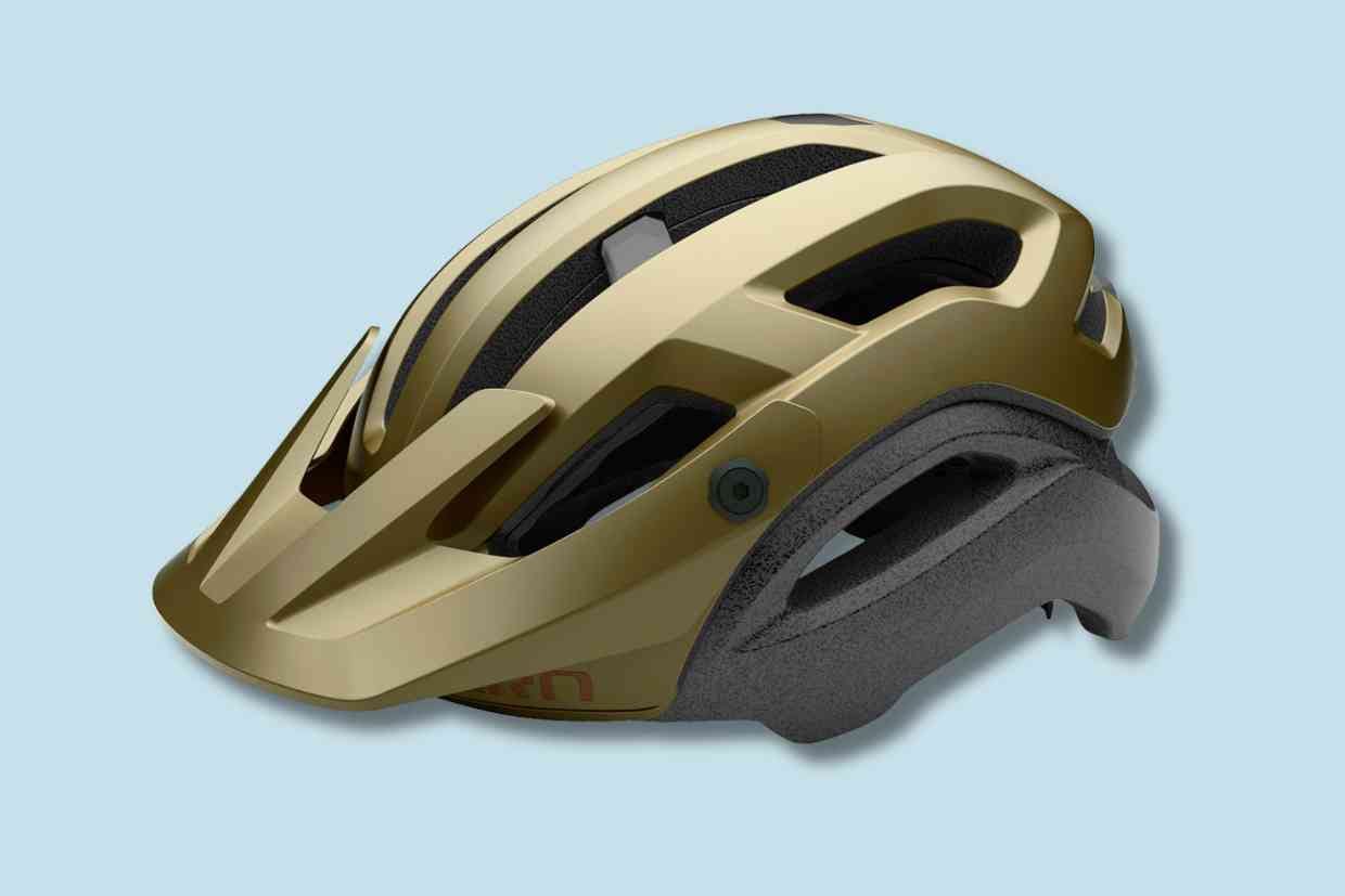 Capacete Giro Manifest Spherical cor bronze e cinza, numa vista em prespectiva e sobreada num fundo azul-claro.
