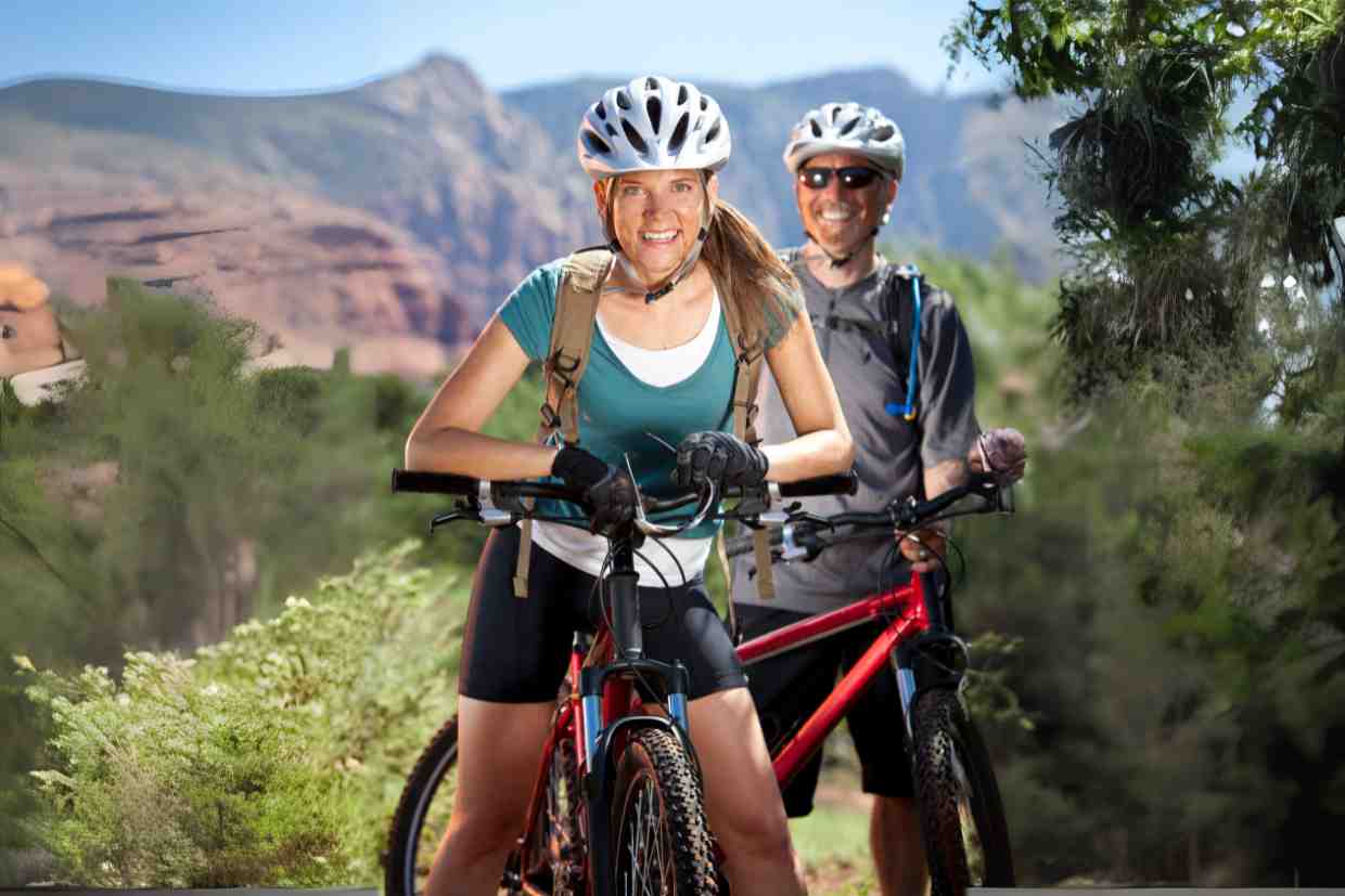 Casal de ciclistas em trilha usando capacete para MTB com visual montanhoso ao fundo.