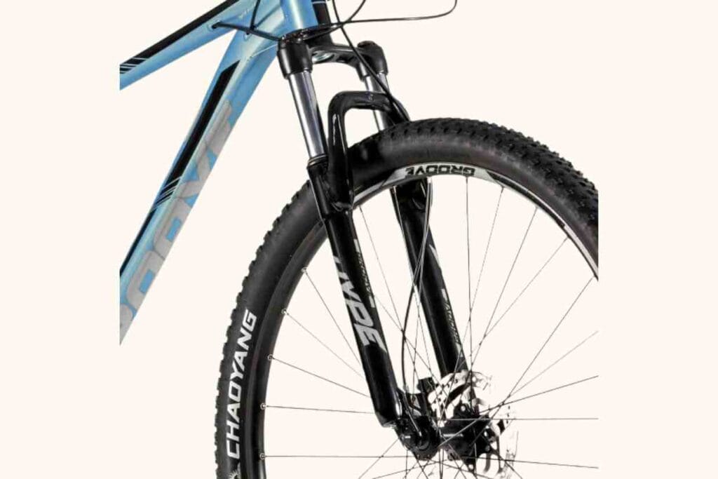 Detalhe do quadro azul e cabeamento interno da bike Groove Hype 70 com close na suspensão dianteira.