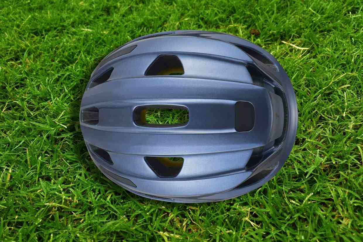 Imagem do capacete de ciclismo Specialized Align II azul-petróleo visto de cima, colocado sobre um gramado verde.