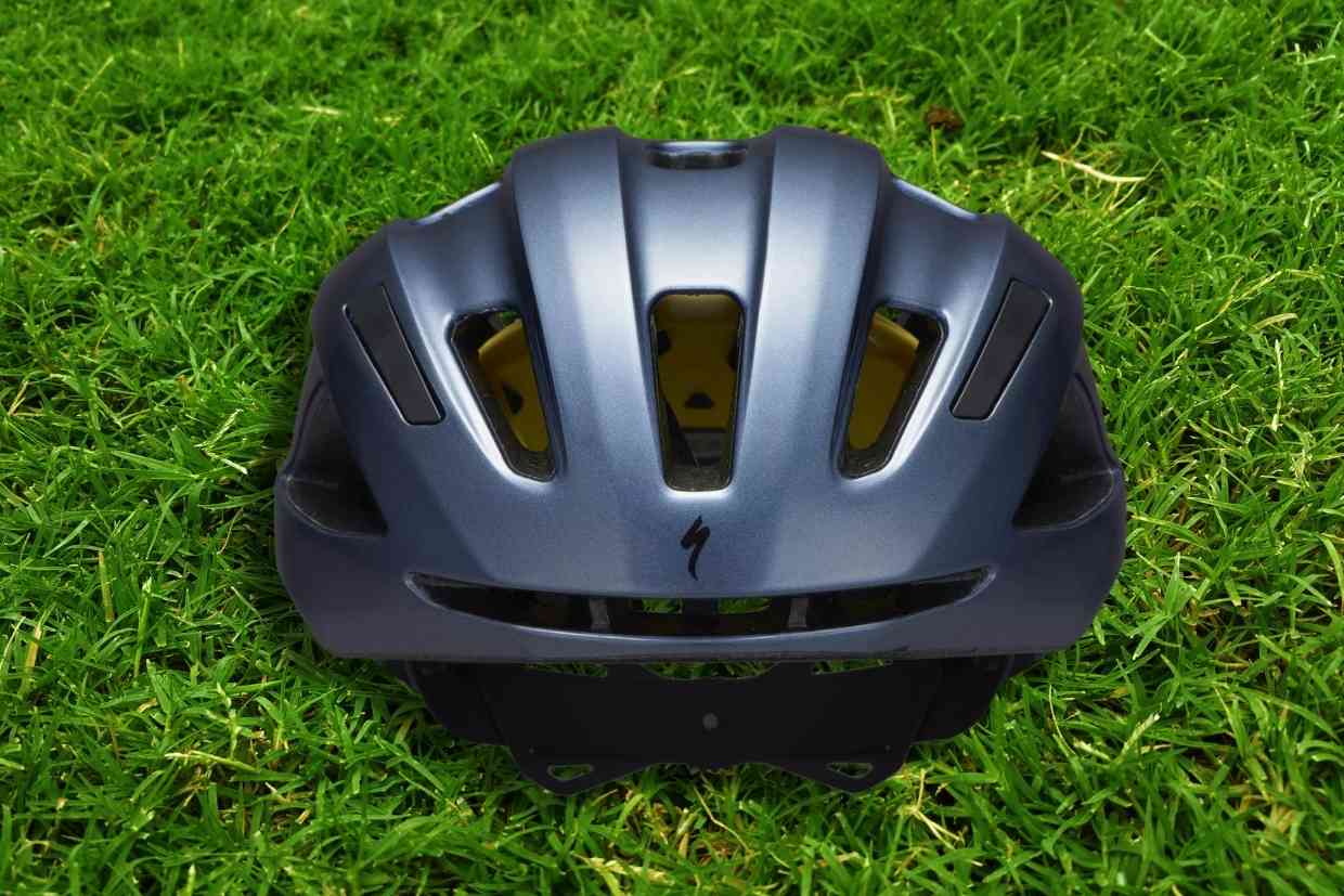 Imagem do capacete de ciclismo Specialized Align II azul-petróleo visto por trás colocado sobre um gramado verde.