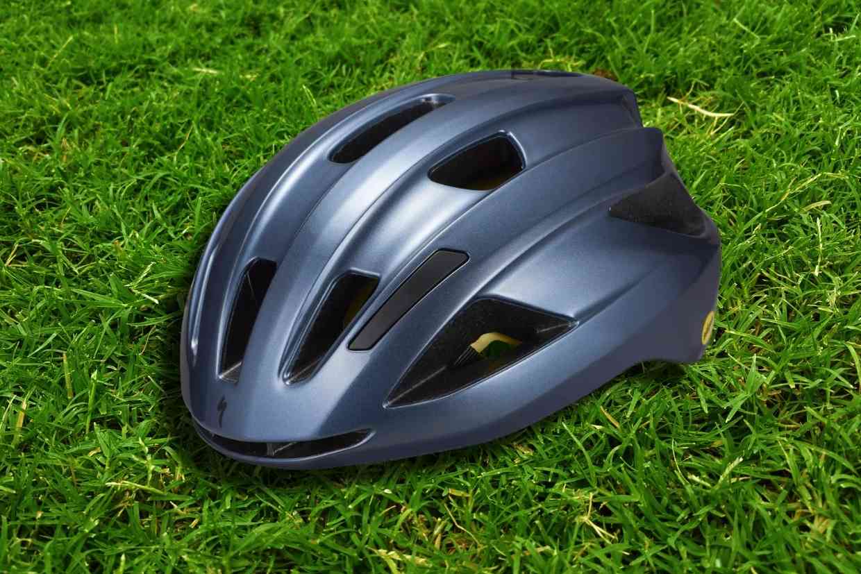 Imagem do capacete de ciclismo Specialized Align II azul petróleo visto em perspectiva sobre uma gramado verde.