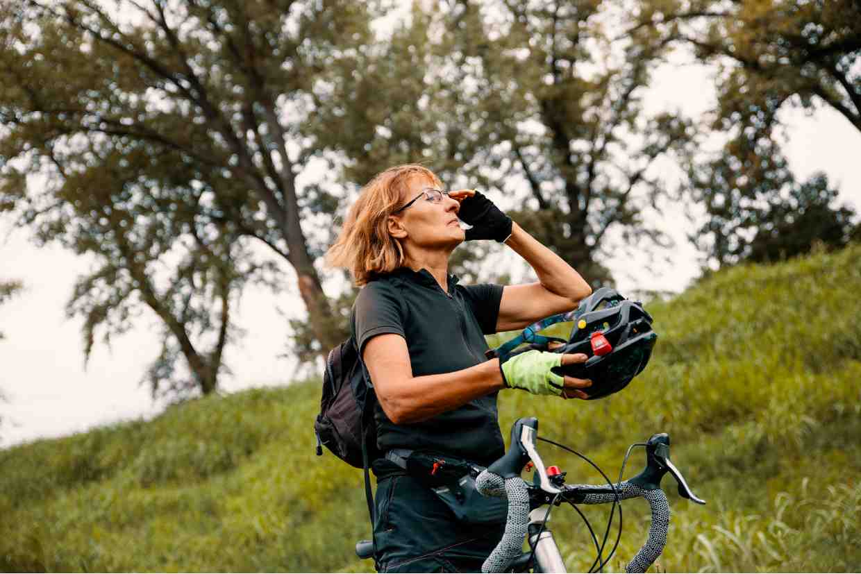 Ciclista segura o capacete e olha ao longe antes do pedal na sua road bike, lembrando que verificar a validade do capacete de ciclismo é passo essencial na preparação.