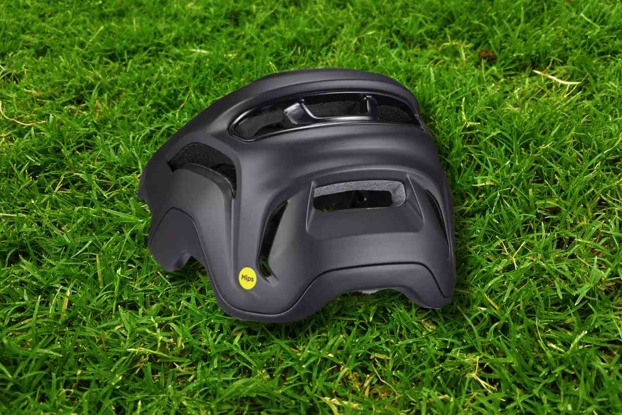 Capacete Specialized Specialized Ambush 2 cinza colocado sobre o gramado, mostrando detalhes da parte de trás com seu ajuste preciso à cabeça.