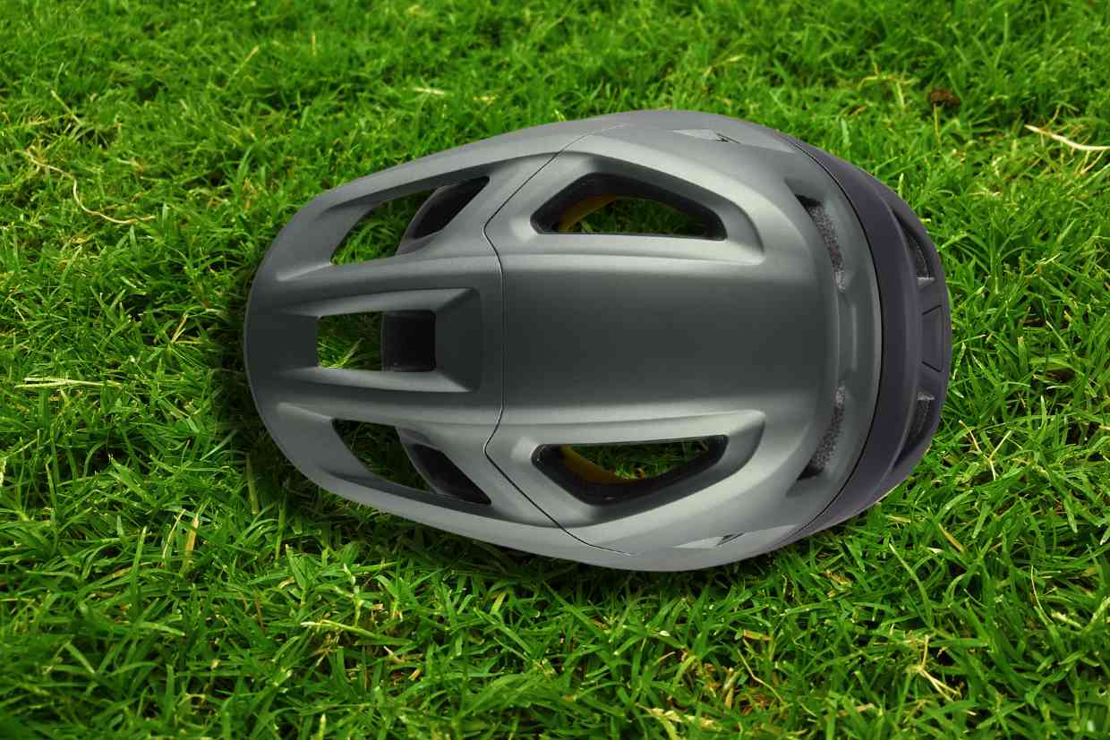 Capacete Specialized Camber cinza colocado sobre o gramado com seu topo virado para cima, mostrando os detalhes das suas entradas de ar.