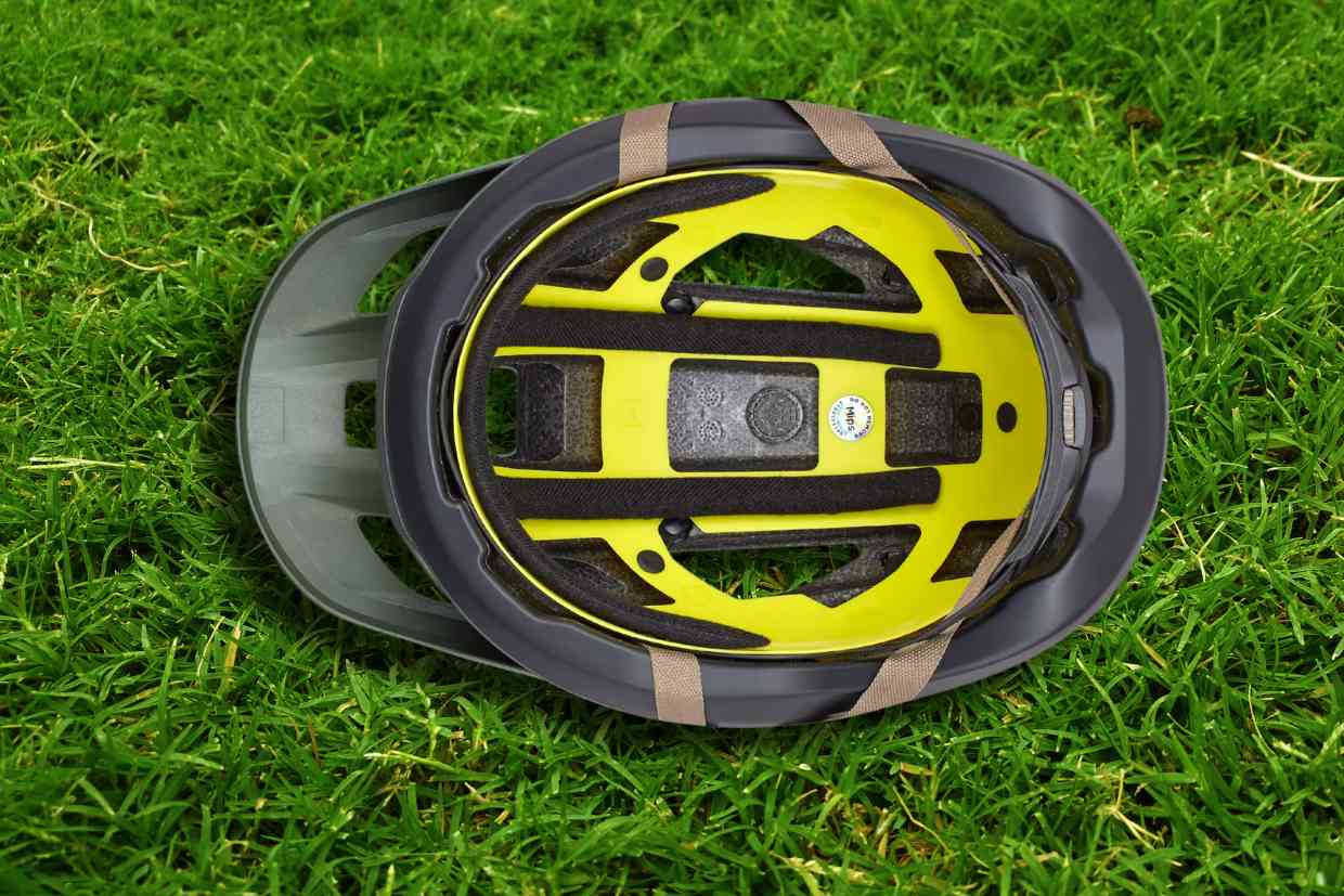 Capacete Specialized Camber cinza colocado sobre o gramado com seu fundo acolchoado virado para cima.