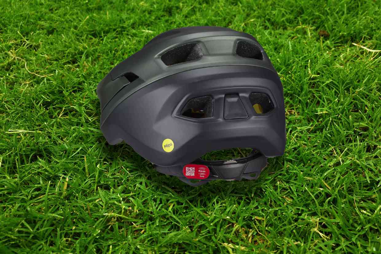 Capacete Specialized Camber cinza colocado sobre o gramado em perspectiva, mostrando detalhes da parte de trás com seu ajuste preciso à cabeça.