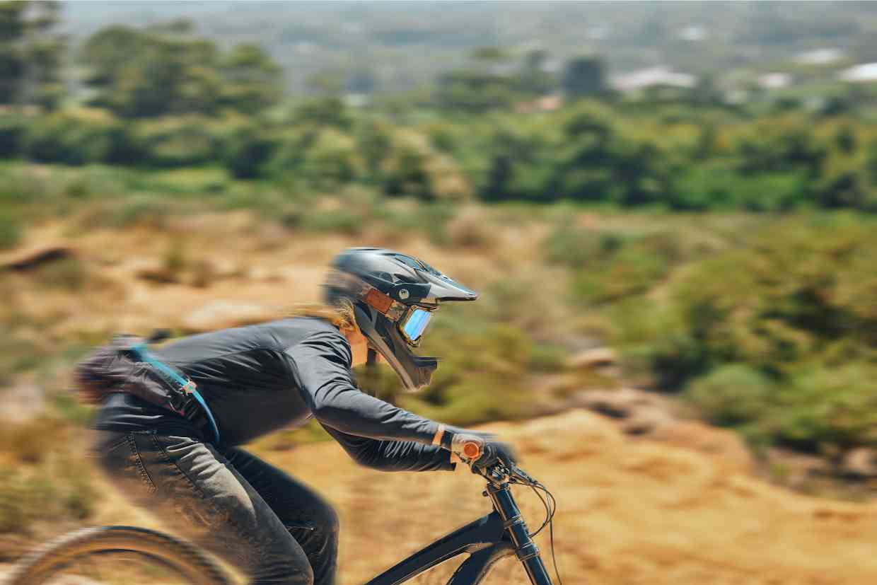 Ciclista em alta velocidade desce uma trilha de downhill usando equipamentos de segurança, como o capacete GIRO SWITCHBLADE MIPS.