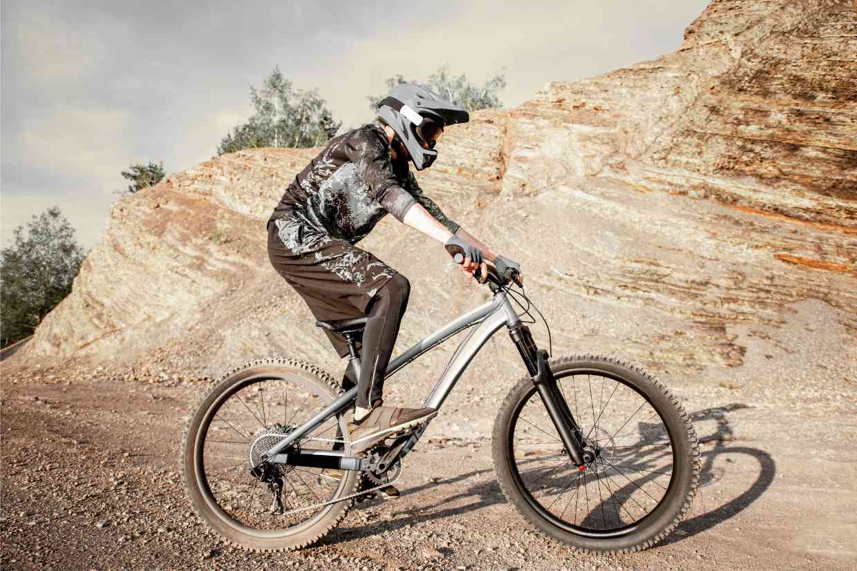 Ciclista numa bike de MTB pedala numa estrada de terra usando seu capacete GIRO SWITCHBLADE MIPS para proteção full face.