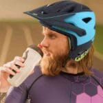 Ciclista se hidratando, usando roupas para ciclismo e vestindo o capacete GIRO SWITCHBLADE MIPS para sua proteção.