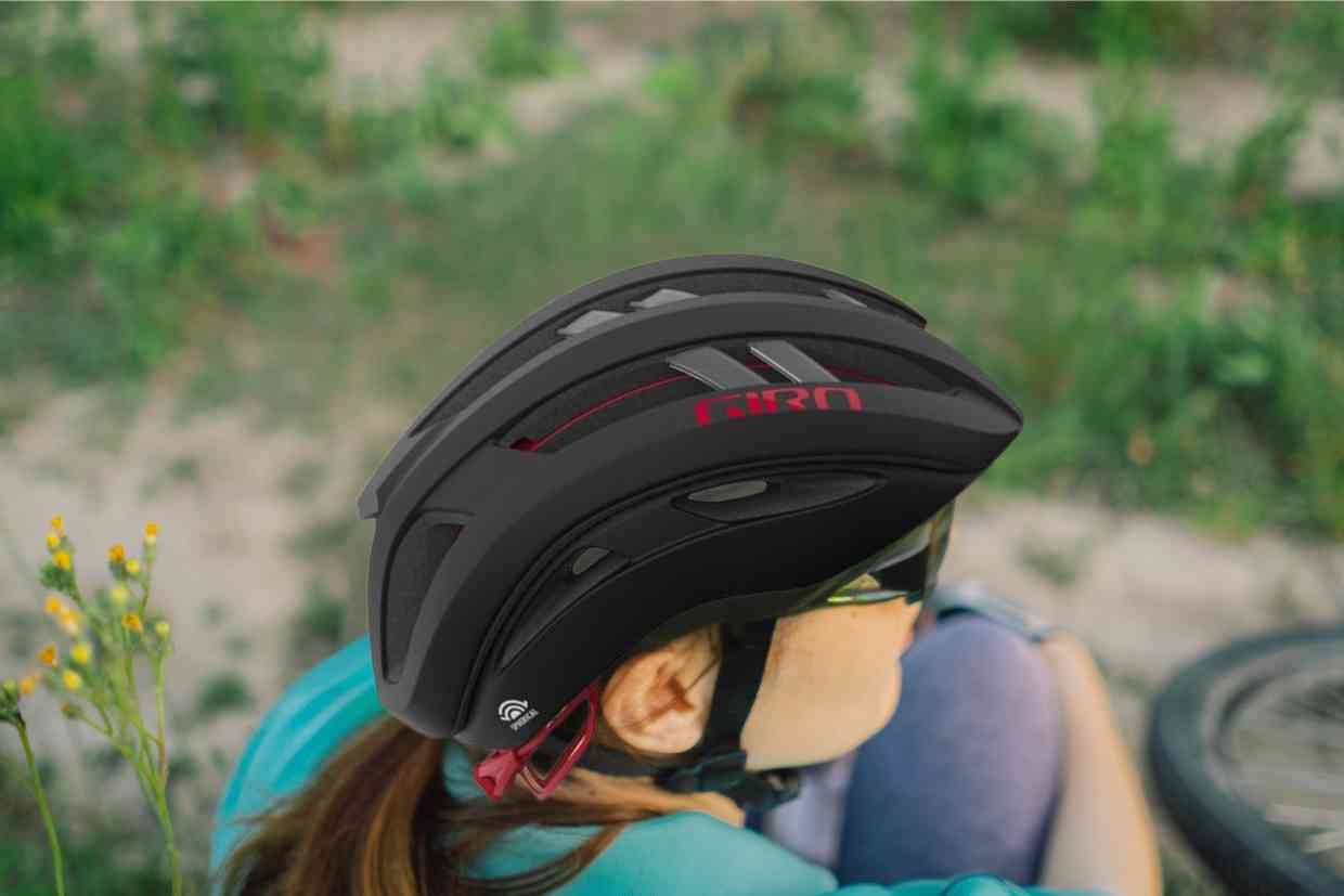 Ciclista sentada no chão, abraçando as pernas e usando o Giro Aries Spherical.