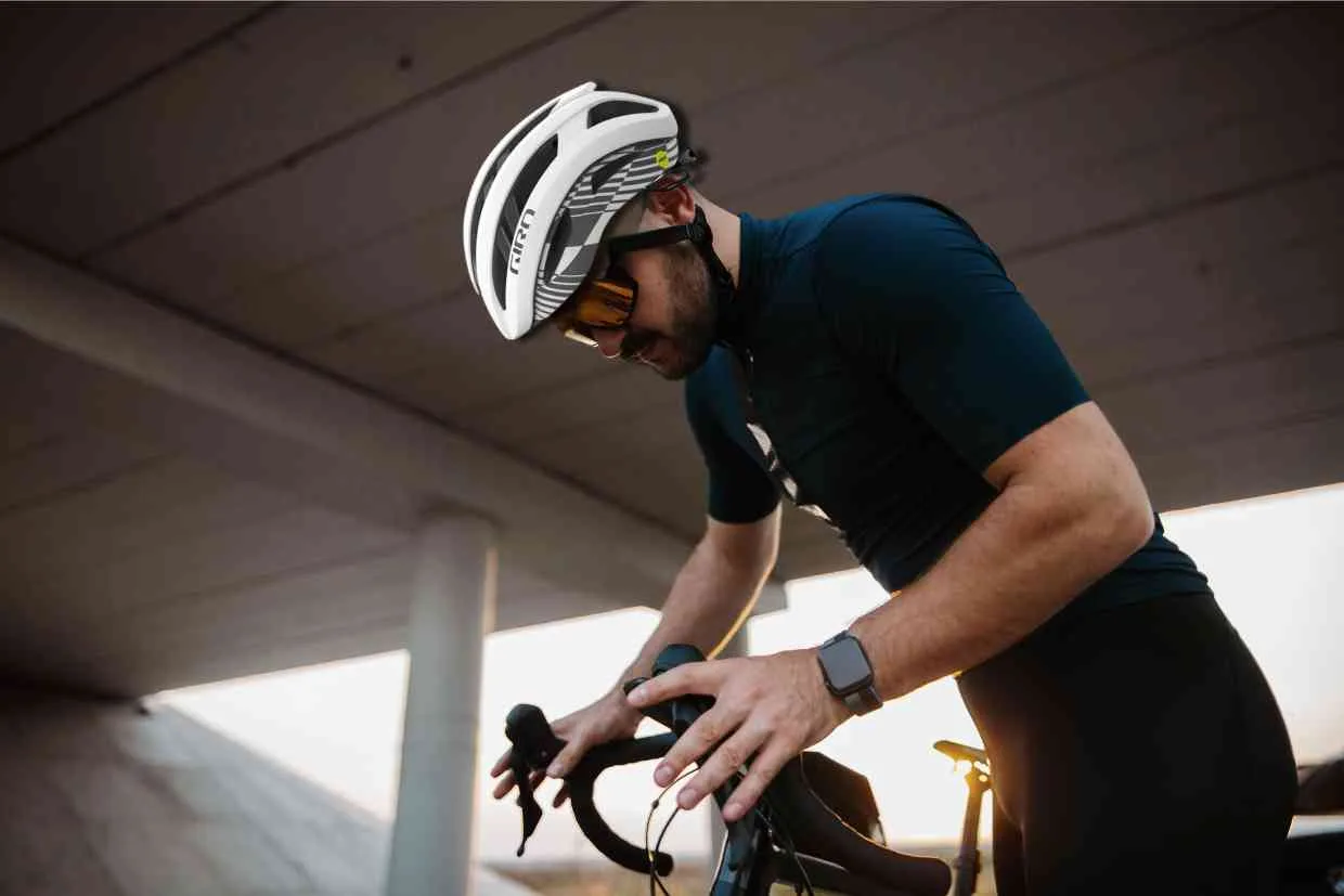 Ciclista de pé, usando seu capacete Giro Aries Spherical enquanto ajusta sua bike.