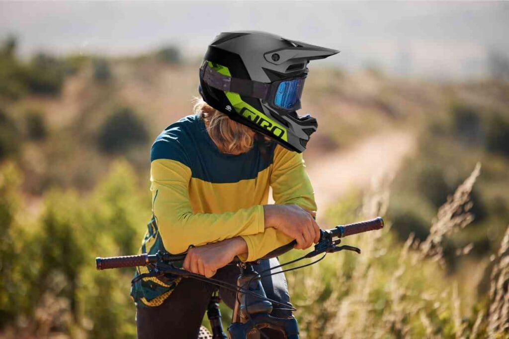 Ciclista de mountain bike descansa enquanto observa a paisagem usando seu capacete Giro Insurgent Spherical.