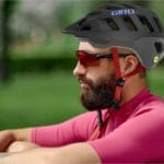 Ciclista sentado no chão com olhar fixo a frente, vestindo uma camisa rosa e o capacete Giro Radix MIPS cinza na cabeça.