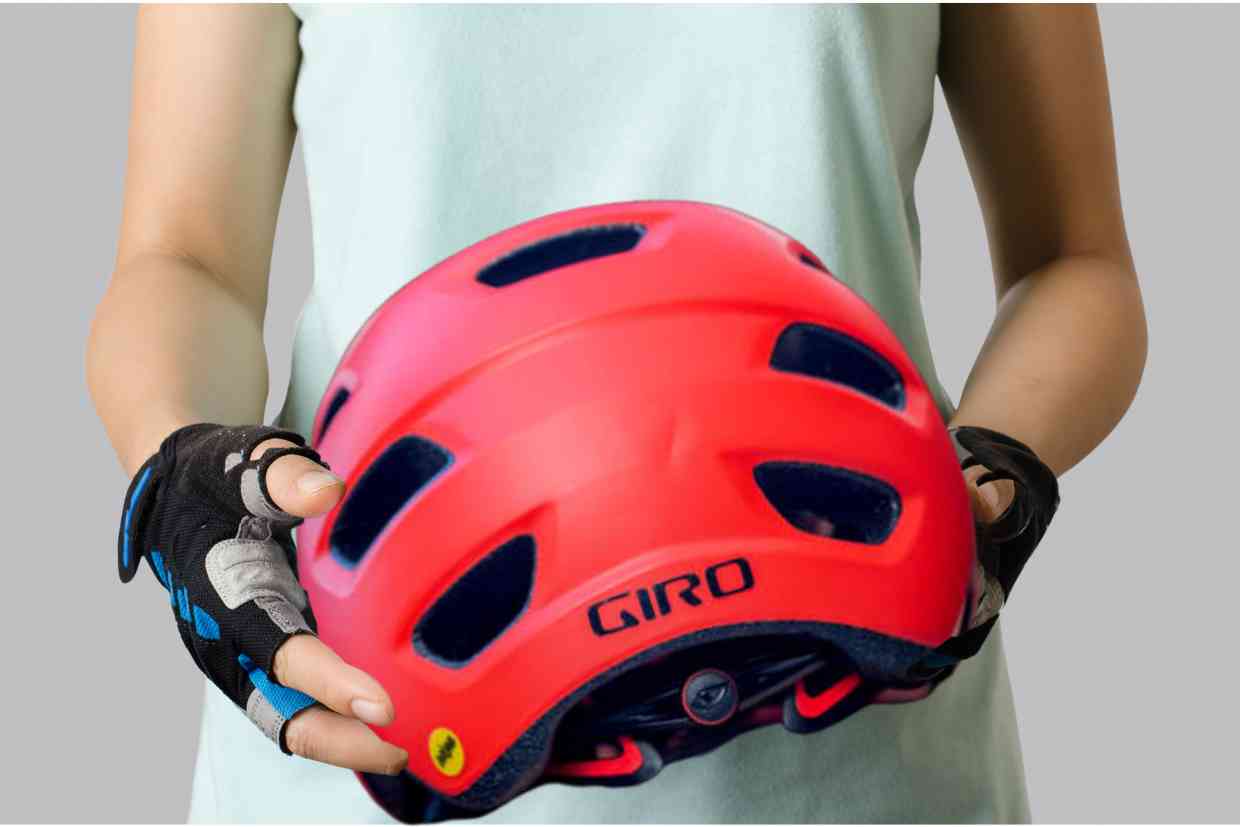 Ciclista segura seu capacete mtb Giro Chronicle MIPS vermelho a frente do corpo.