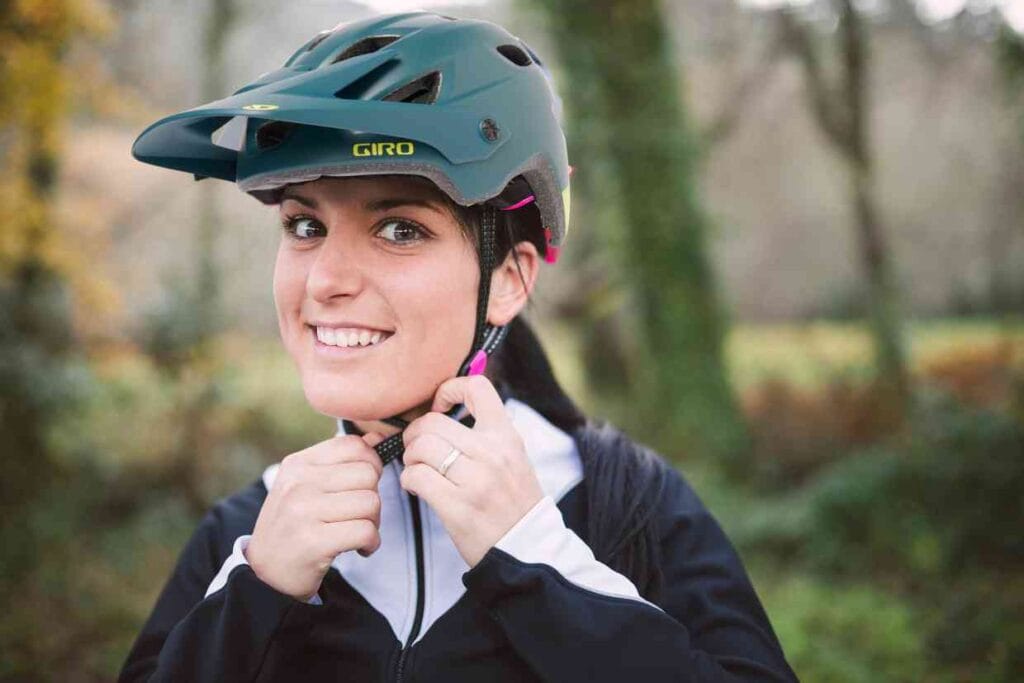 Uma ciclista ajusta seu capacete Giro Chronicle MIPS na cabeça.