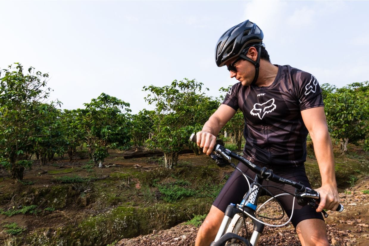 Ciclista observa a trilha técnica, sentado na sua bike MTB e usando bermuda Barbedo Sprint preta.